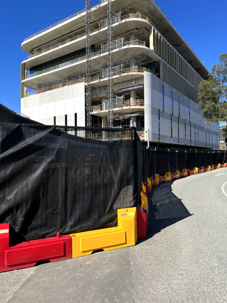Gallery: Building under construction with a construction elevator, safety fence, and concrete structure, showcasing architectural progress.
