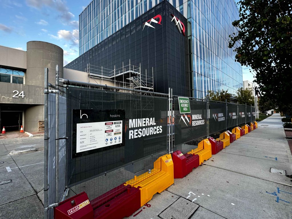 Gallery: Mineral Resources building with construction fencing. Scaffolding visible. Emergency assembly area sign. Hoskins logo on fence.